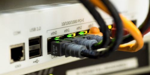 Detailed close-up of ethernet cables and network connections on a router, showcasing modern technology.